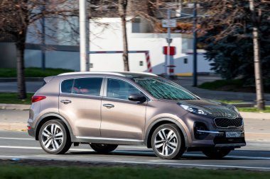 Moskova; Rusya - 14 Ekim 2021: Kahverengi Kia Sportage sıcak bir sonbahar gününde bir parkın arka planına doğru hızla sürüyor