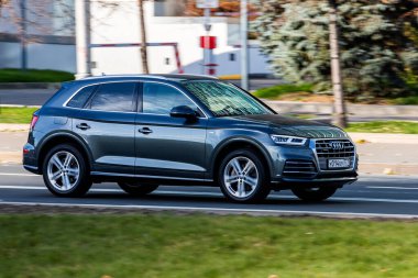 Moskova; Rusya - 14 Ekim 2021: Siyah Audi Q5 sıcak bir sonbahar gününde bir parkın arka planına doğru hızla ilerliyor