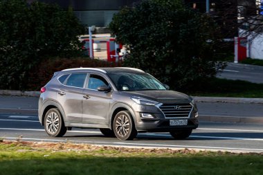Moskova; Rusya - 14 Ekim 2021: Siyah Hyundai Tucson, sıcak bir sonbahar gününde bir parkın arka planına doğru hızla sürmektedir.
