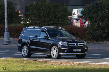 Moskova; Rusya - 14 Ekim 2021: Siyah Mercedes-Benz GL sınıfı sıcak bir sonbahar gününde bir parkın arka planına doğru hızla sürüyor