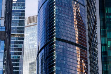 Şeffaf duvarları olan yüksek teknolojili ofis binası bulutlu parlak mavi gökyüzünü yansıtıyor. Modern mimari. Soyut cam arkaplan