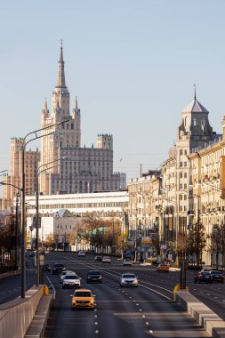 Moskova; Rusya - 13 Ekim 2021: işlek bir şehir caddesi, bir park ve eski binaların bulunduğu bir sokak Kudrinskaya Meydanı 'ndaki iskan binasının arka planına karşıdır. 