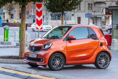 Moskova, Rusya - 13 Ekim 2021: Red Smart Fortwo, sıcak bir sonbahar gününde bir binanın arka planına park etti.