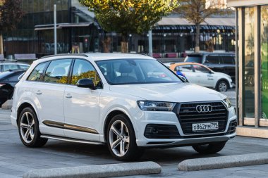 Moskova, Rusya - 13 Ekim 2021: Beyaz Audi Q7, sıcak bir sonbahar gününde park alanının arka planına park edilmiştir.