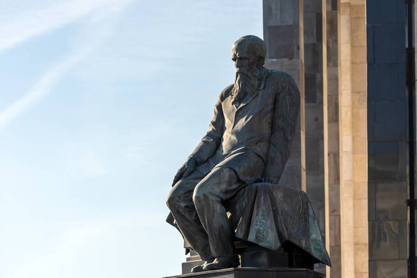 Москва, Россия - 14 октября 2021 года: памятник Федору Достоевскому крупным планом на заднем плане Государственной библиотеки СССР им. Ленина