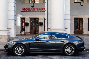Moskova; Rusya - 15 Ekim 2021: Siyah Porsche Panamera, sıcak bir sonbahar gününde bir binanın arka planına karşı sokağa park edilmiştir.