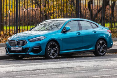 Moskova; Rusya - 15 Ekim 2021: Mavi BMW 2 serisi sıcak bir günde sonbahar parkının arka planına park edilmiştir. 