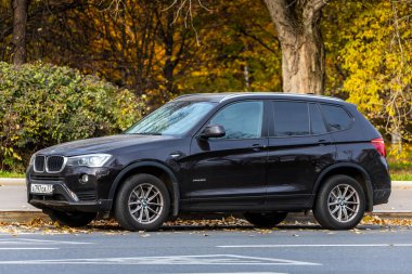 Moskova; Rusya - 15 Ekim 2021: Siyah BMW X3, sıcak bir günde sonbahar parkının arka planına park edilmiştir. 