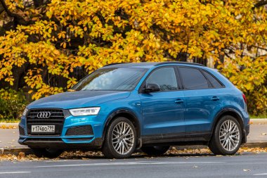 Moskova; Rusya - 15 Ekim 2021: Mavi Audi Q3, sıcak bir günde sonbahar parkının arka planına park edilmiştir. 