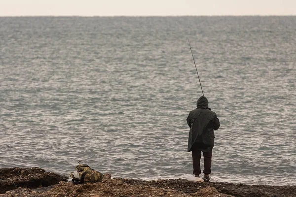 Ein Männlicher Fischer Mit Schwarzem Regenmantel Fängt Winter Fische Auf — Stockfoto