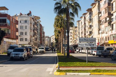 Manavgat, Türkiye - 20 Ocak 2022: Düşük katlı evleri, aktif araba trafiği, dükkanları olan şehir caddesi