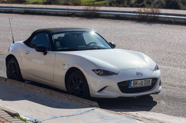 Yan, Türkiye - 19 Ocak 2022: Beyaz Mazda Miata coupe, sıcak bir günde bir binanın arka planına, ağaçlara karşı sokağa park edilmiştir.