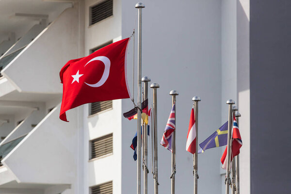 National flag of Turkey on a flagpole waving in backdrop many others flags
