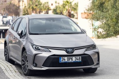 Yana, Türkiye - 22 Ocak 2022: Gümüş renkli Toyota Corolla, sıcak bir günde bir binanın, ağaçların, dükkanların zeminine park etti.