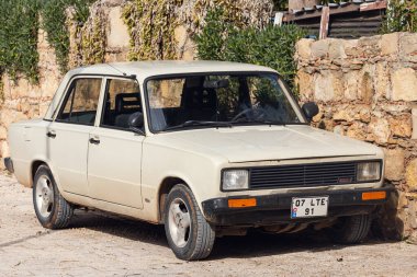 Yan, Türkiye - 22 Ocak 2022: Bej renkli Tofas, sıcak bir günde bir yan tarih merkezinin arka planına karşı sokağa park edilmiştir.