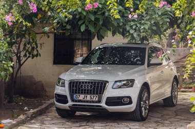 Yana, Türkiye - 22 Ocak 2022: Beyaz Audi Q5 sıcak bir günde mor bir çiçek gölgesinin altında özel bir evin avlusuna park etti. 
