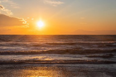Sahildeki güzel günbatımı gökyüzünün ve güneşli bir günde parlak okyanusun manzarası.