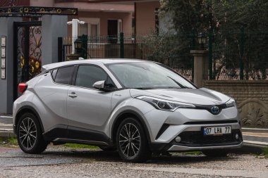 Yana, Türkiye - 23 Ocak 2022: Gümüş rengi Toyota Ch-r, sıcak bir günde bir binanın, ağaçların, dükkanların zeminine park etti.