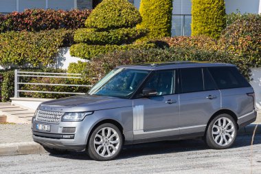 Yana, Türkiye - 22 Ocak 2022: Gümüş Land Rover Rover sıcak bir günde bir çitin arka planına, bahçeye park etti.