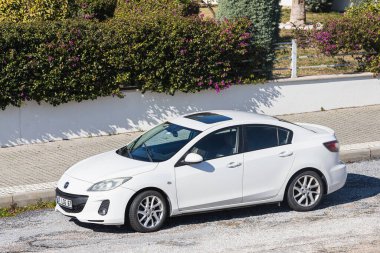 Yana, Türkiye - 22 Ocak 2022: Beyaz Mazda 3, sıcak bir günde bir çitin arka planına, bahçeye park edilmiştir.