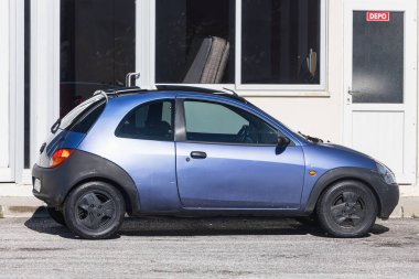Yana, Türkiye - 22 Ocak 2022: Mavi Ford Ka sıcak bir günde bir çitin arka planına, bahçeye park etti.