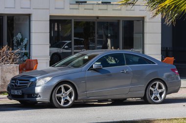 Yana, Türkiye - 22 Ocak 2022: Gümüş Mercedes-Benz E-coupe sıcak bir günde bir çitin arkasına park etti
