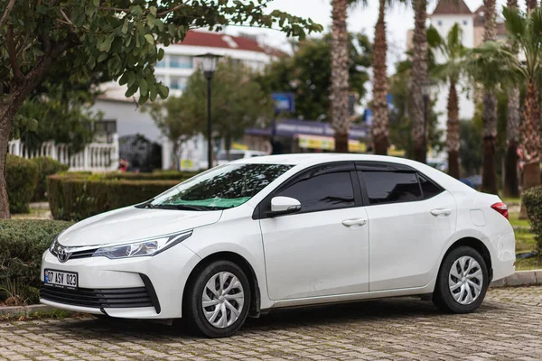 Yan, Türkiye - 25 Ocak 2022: Beyaz Toyota Corolla, sıcak bir yaz gününde parka karşı park halinde.