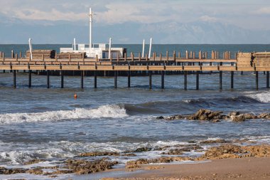 Güzel deniz pantonu ve plaj. Otelin kumlu sahilinde büyük bir ahşap iskele var. Uzun pantolonlu güzel tropikal sahil manzarası. Deniz kıyısının manzarası