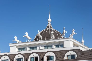 Kar beyazı otelin dış görünüşü ve at heykelleri. Tavan arası