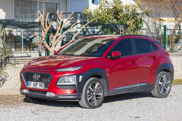 Yana, Türkiye - 27 Ocak 2022: Kırmızı Hyundai Kona bir yaz günü bir çitin arkasına park ediyor.