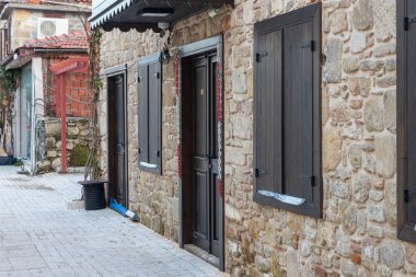 Tahta kapılı, pencereli ve panjurlu taş bir evin duvarını kapatın. Eski Avrupa mimarisi