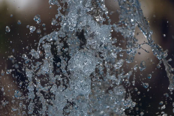 Струи Воды Большим Количеством Капель Пузырьков Лучами Солнца Синем Фоне — стоковое фото