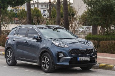 Yana, Türkiye - 27 Ocak 2022: Mavi Kia Sportage bir yaz günü bayraklı bir parkın arka planına park ediyor 