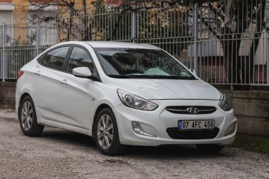 Taraf; Türkiye - 27 Ocak 2022: Beyaz Hyundai Solaris park ediyor; bir yaz günü sokakta bir parkın arka planına karşı