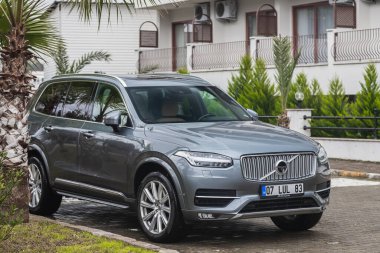 Yana, Türkiye - 30 Ocak 2022: Gümüş Volvo CX90 bir yaz günü bir binanın, ağaçların, dükkanların zeminine park edilmiştir.