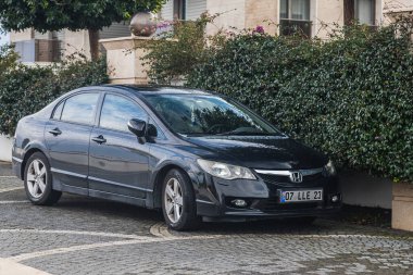 Yan, Türkiye - 30 Ocak 2022: Siyah Honda Civic, sıcak bir yaz gününde otel ve ağaçlara karşı sokağa park etti