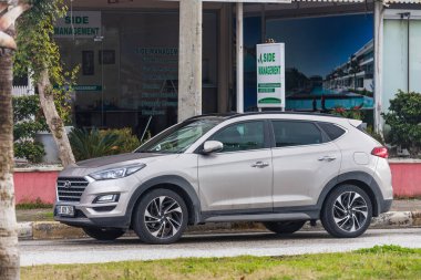 Yan, Türkiye 01 Şubat 2022: bej rengi Hyundai Tucson sıcak bir günde bir dükkanın arka planına karşı sokağa park edildi 