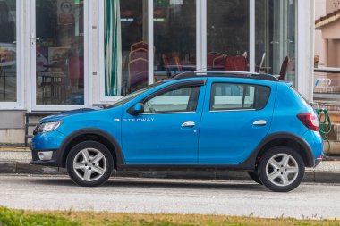 Yana, Türkiye - 25 Ocak 2022: Mavi Dacia Sandero Stepway, sıcak bir yaz gününde kafeye karşı sokağa park etti