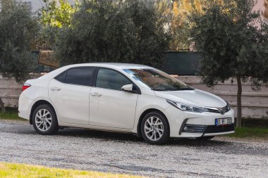 ; Türkiye 01 Şubat 2022: Beyaz Toyota Corolla, sıcak bir günde bir binanın arka planına, ağaçlara karşı sokağa park edilmiştir. 