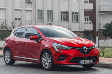 Yan; Türkiye 01 Şubat 2022: Red Renault Clio, sıcak bir yaz gününde bir binanın arka planına karşı sokağa park etti 