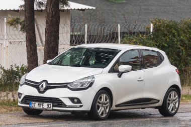 Taraf, Türkiye - 02 Şubat 2022: Beyaz Renault Clio, sıcak bir günde bir binanın arka planına park etti.