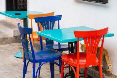 Atmosferik yaz fotoğrafçılığı. Masadaki tahta kafe sandalyeleri. Renkli ahşap sandalyeli açık hava sokak kafesi.