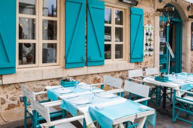 Atmosferik yaz fotoğrafçılığı. Mavi peçetelerle süslenmiş ahşap masalar. Açık sokak kafesi, deniz usulü.