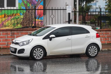 Taraf, Türkiye - 02 Şubat 2022: Beyaz Kia Rio, sıcak bir günde bir binanın arka planına park etti.