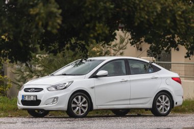 Yana, Türkiye - 02 Şubat 2022: Beyaz Hyundai Solaris sıcak bir günde bir parkın arka planına, çitlere park etti.