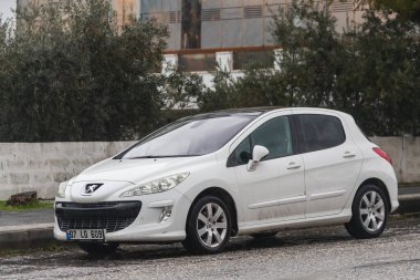 Yana, Türkiye - 02 Şubat 2022: Beyaz Peugeot 308, sıcak bir günde bir parkın arka planına, çitlere park edilmiştir.