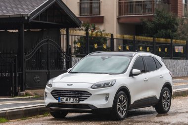 Taraf, Türkiye - 2 Şubat 2022: Beyaz Ford Kuga, sıcak bir günde bir bina, park, çit zeminine karşı sokağa park etti