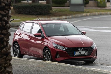 Yan, Türkiye 2 Şubat 2022: Kırmızı Hyundai i20 bir yaz gününde bir parkın arka planına park ediyor 