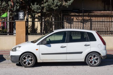 Yana, Türkiye - 02 Şubat 2022: Beyaz Ford Fiesta sıcak bir sonbahar gününde sokağa park edildi 