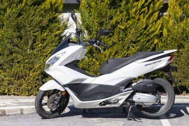    Taraf, Türkiye 2 Şubat 2022: Sıcak bir günde, sokağın arka planında beyaz bir motosiklet duruyor  